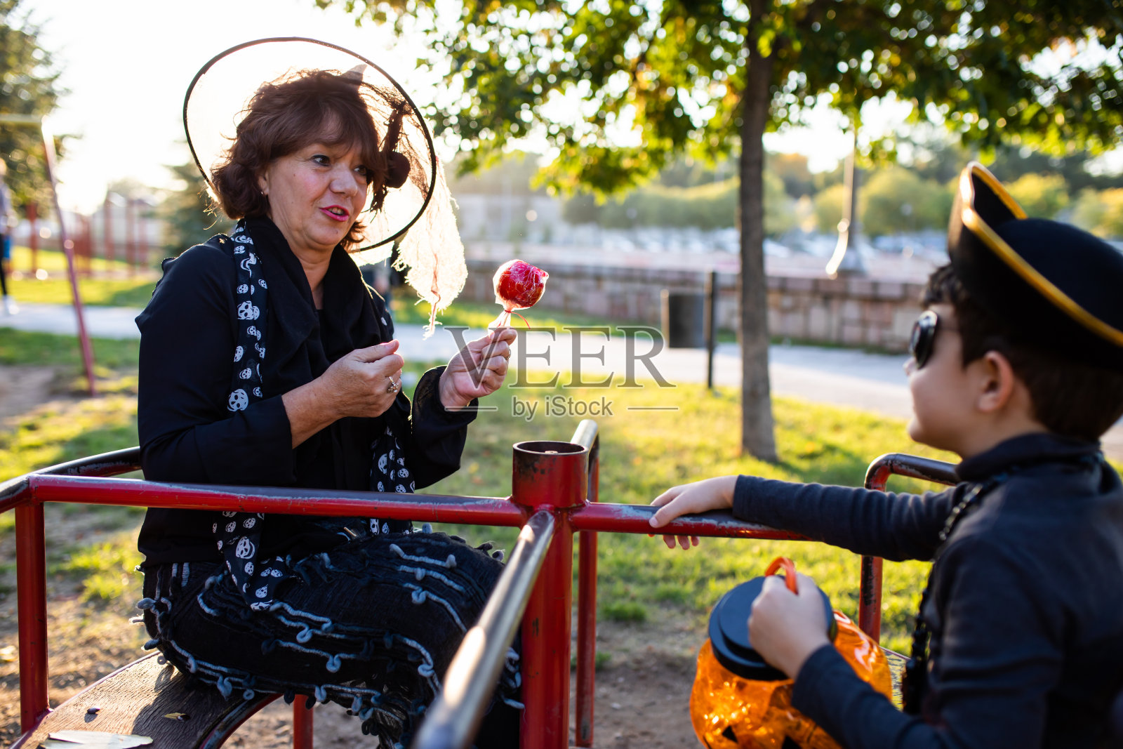 一个穿着女巫服装的老奶奶给她的海盗孙子一个蜜饯苹果照片摄影图片