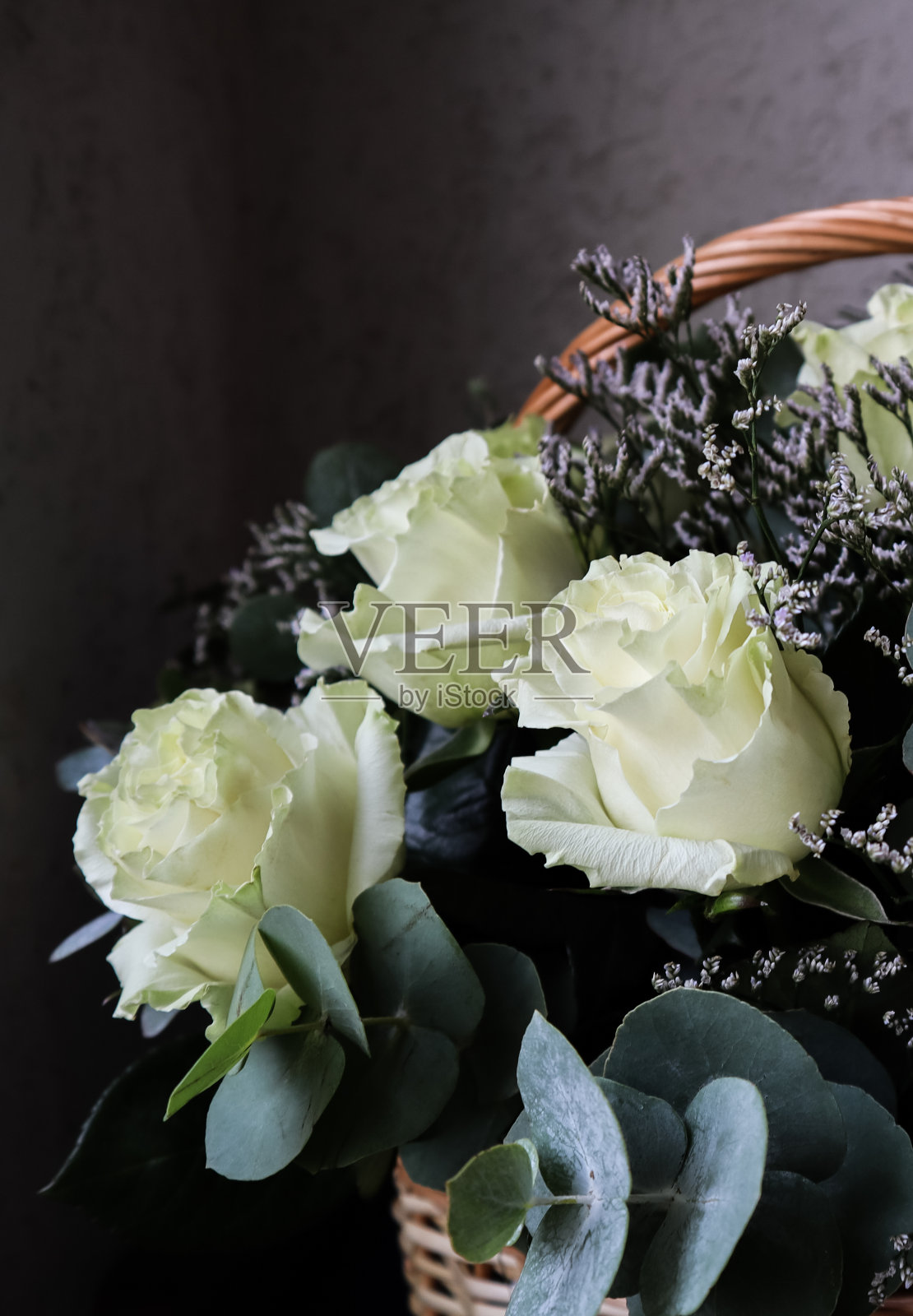 一束美丽的白玫瑰在柳条篮子在黑暗的背景。完美的贺卡照片摄影图片