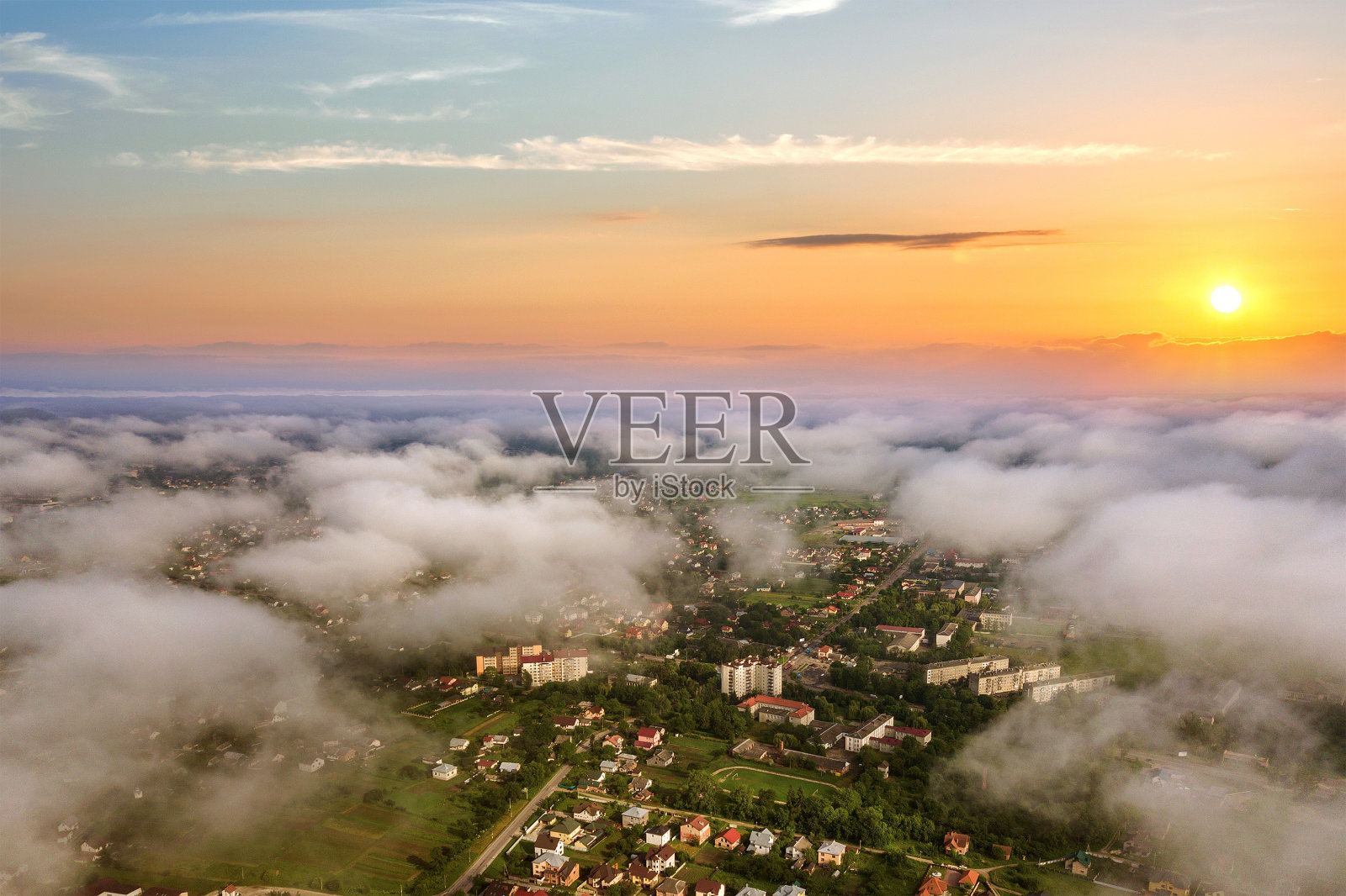 日落在农村地区的城市与云彩和黄色的太阳。照片摄影图片