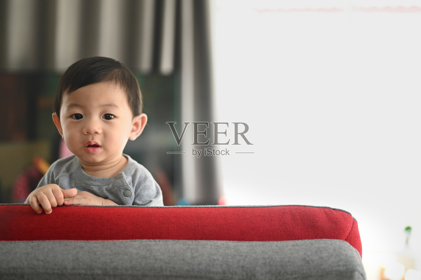 宝宝站在客厅的沙发上。照片摄影图片