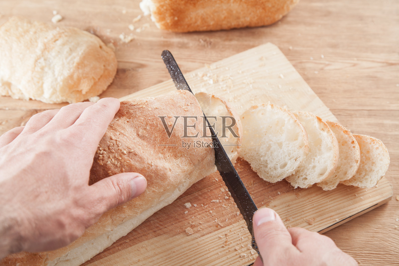 正在切面包的白人。健康的食物照片摄影图片