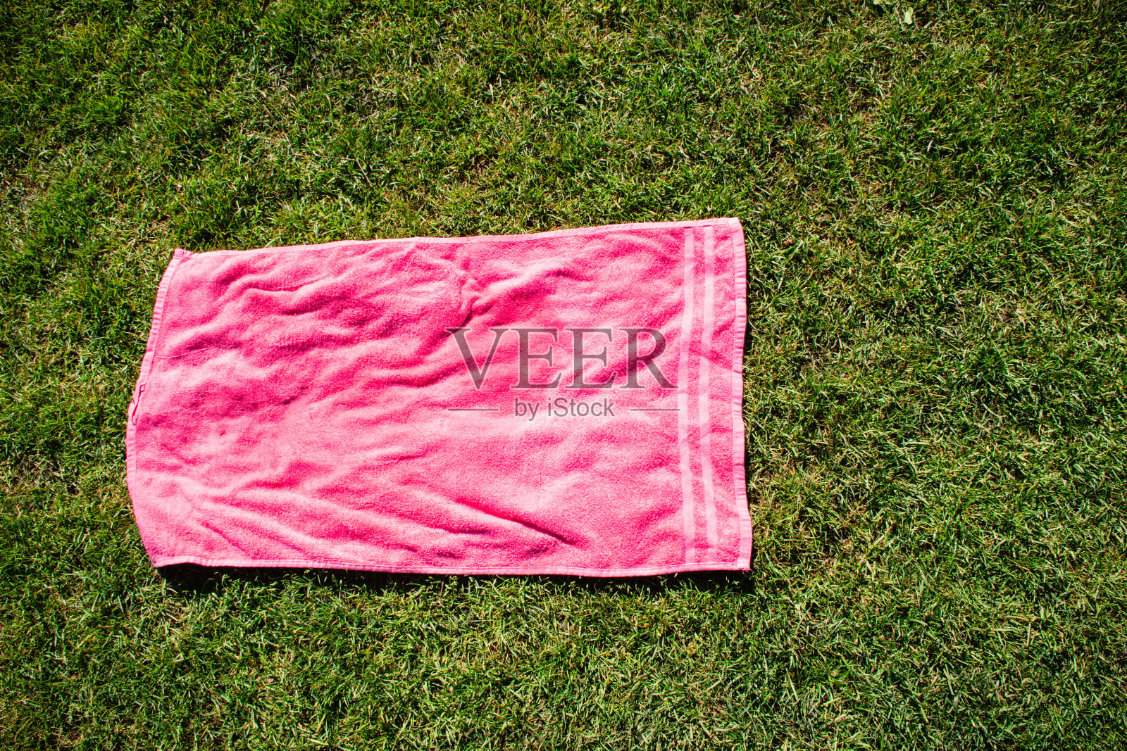 绿色草地上的粉色毛巾照片摄影图片