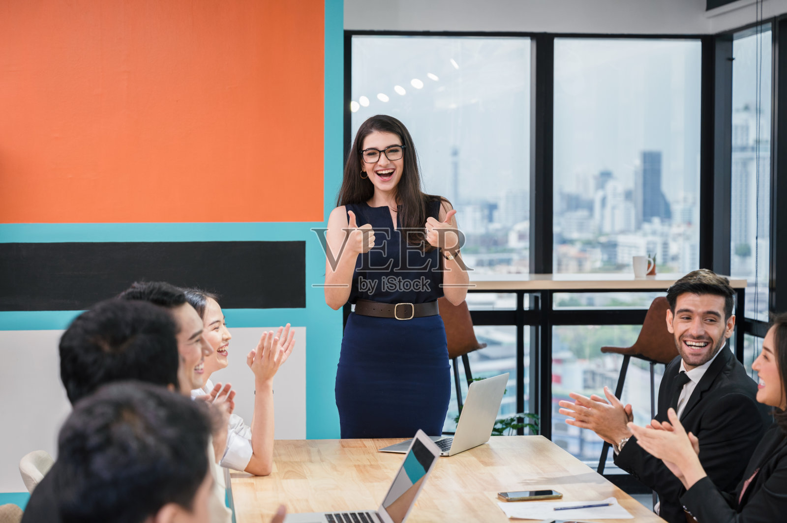 会议期间，一名白人女主管高兴地向多种族同事竖起大拇指，鼓掌祝贺照片摄影图片