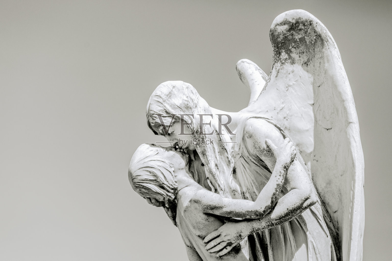 黑白老雕像的角度亲吻小男孩，背景与复制空间照片摄影图片