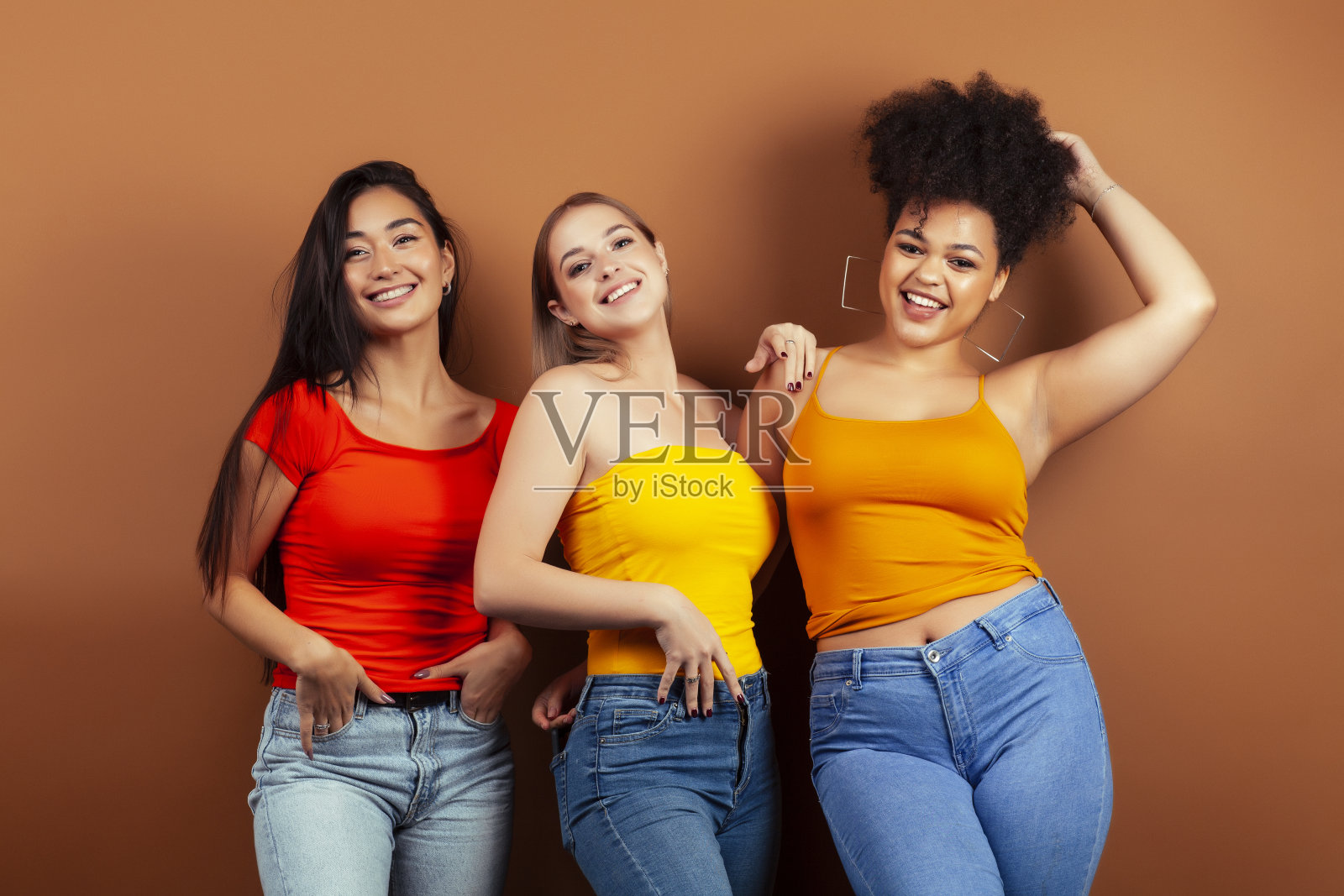 年轻漂亮的多种族女孩摆出愉快的棕色背景，生活方式的人的概念照片摄影图片