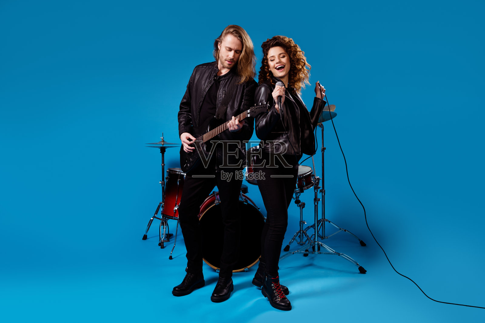 正著名艺人团队两人合照，男人弹吉他，女人唱歌，麦克风作曲，有夜店表演活动孤立亮亮的蓝色背景照片摄影图片