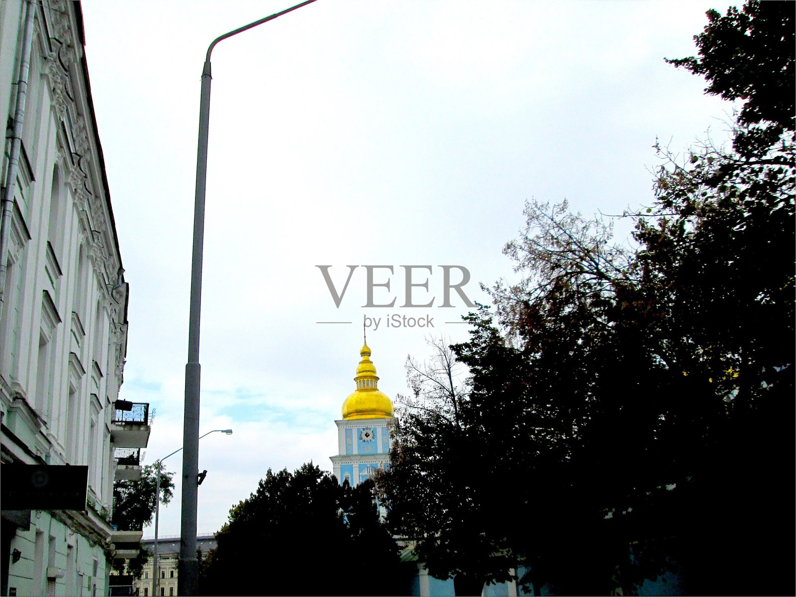 秋色多云，金色的东正寺塔从老城区绿树成荫的街道照片摄影图片