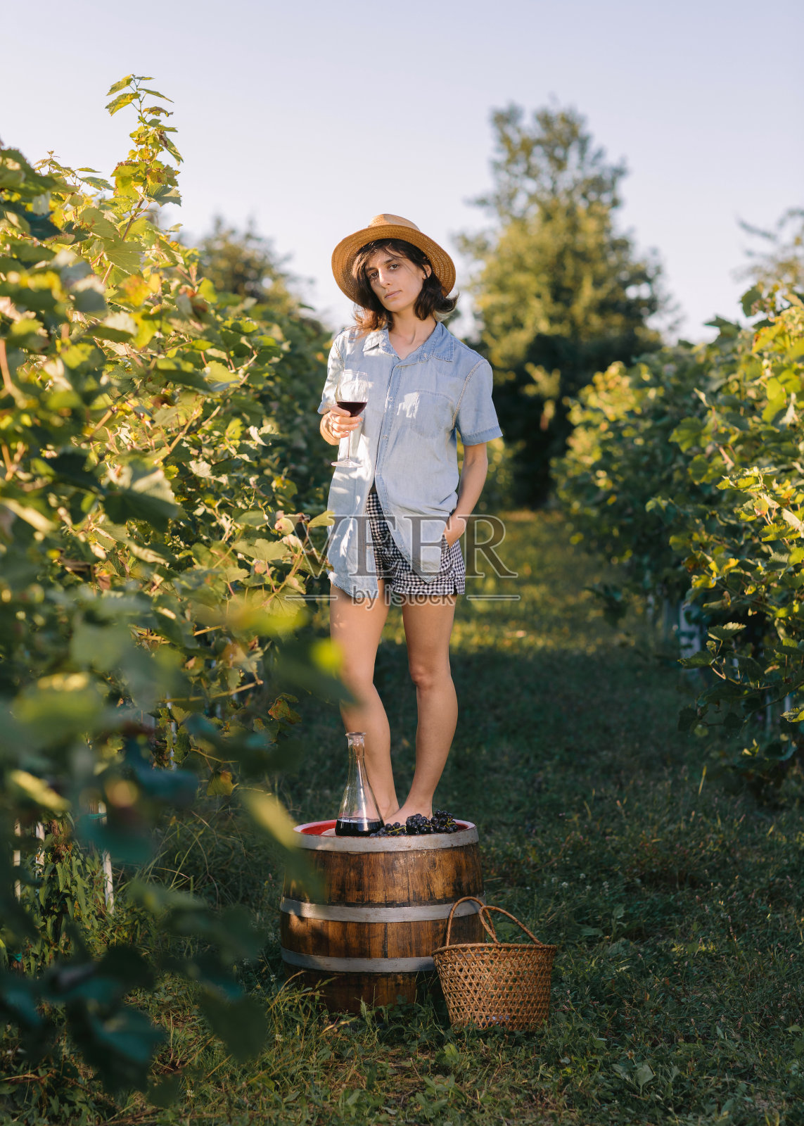女人站在酒桶上，拿着酒杯。照片摄影图片