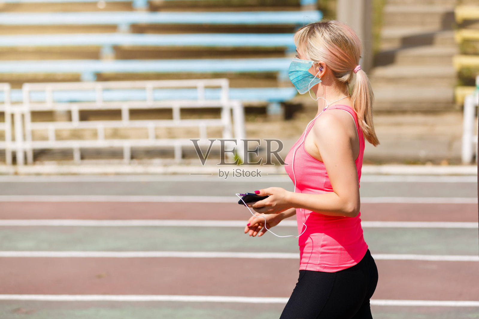 冠状病毒新型冠状病毒肺炎妇女在隔离期间做运动，戴口罩保护。预防传染病。社会距离。监禁。照片摄影图片