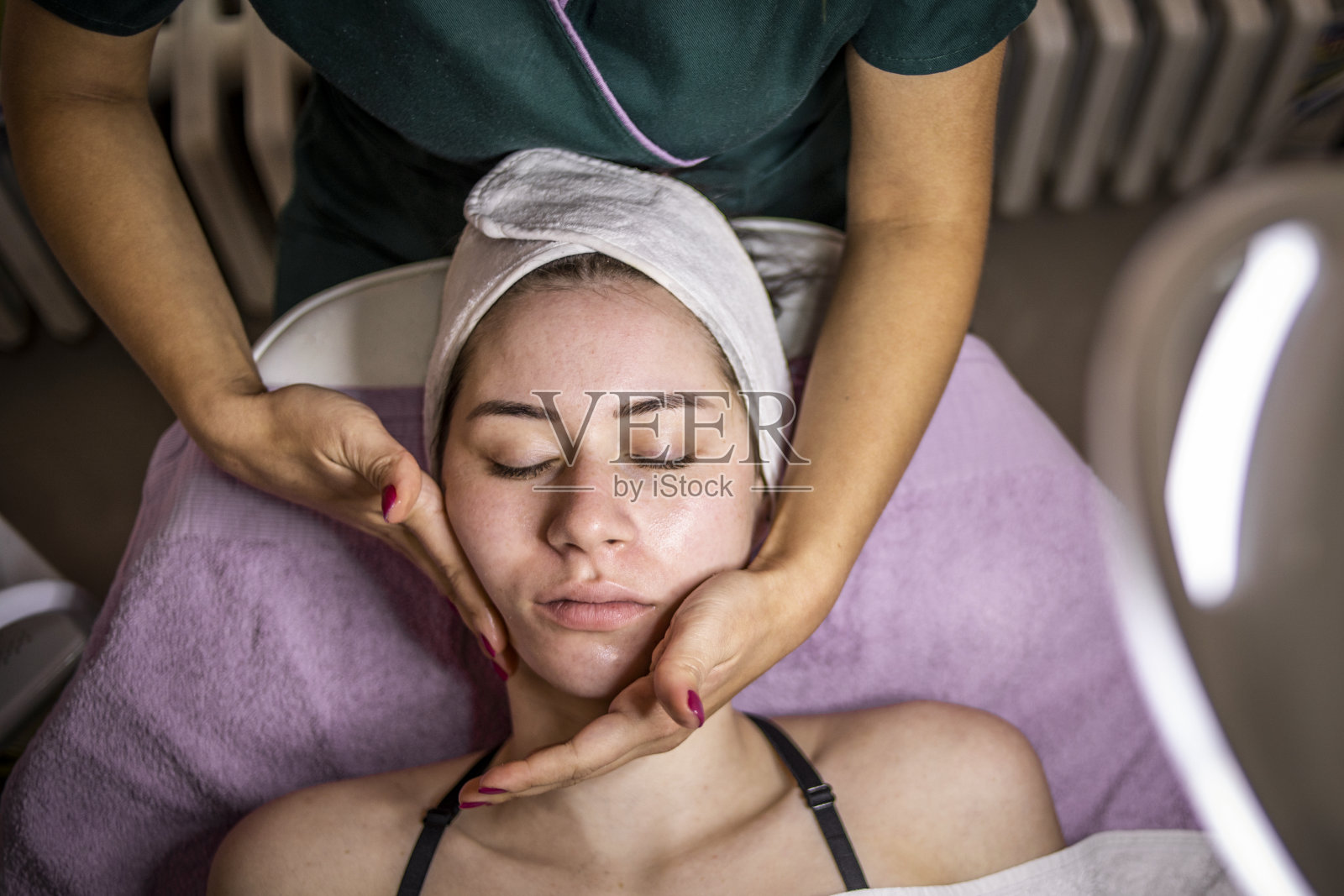 美丽的女人在水疗沙龙的面部按摩-抗衰老疗法-年轻化和面部清洁照片摄影图片