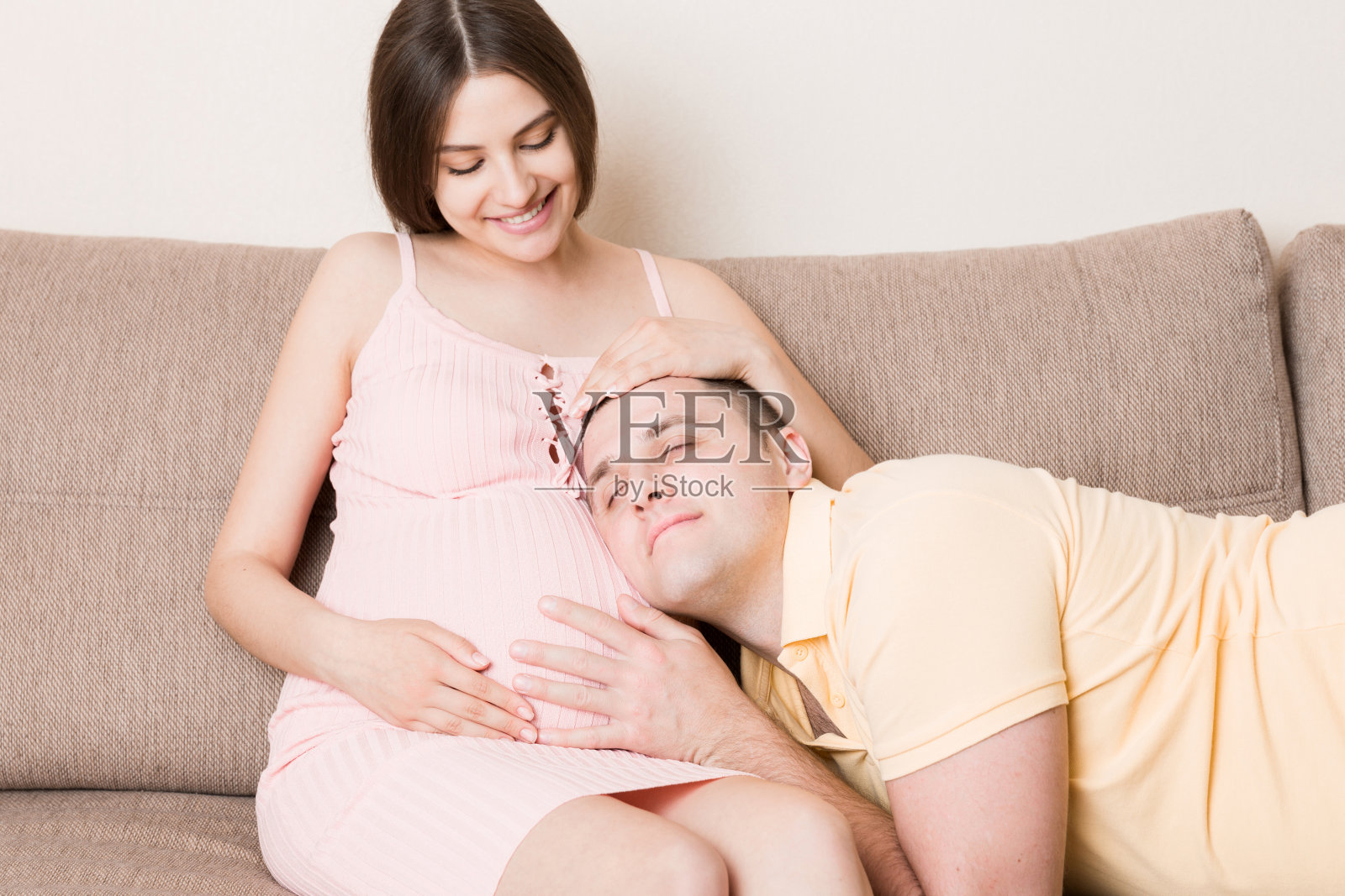 男人在家听着怀孕妻子的肚子，面带微笑照片摄影图片