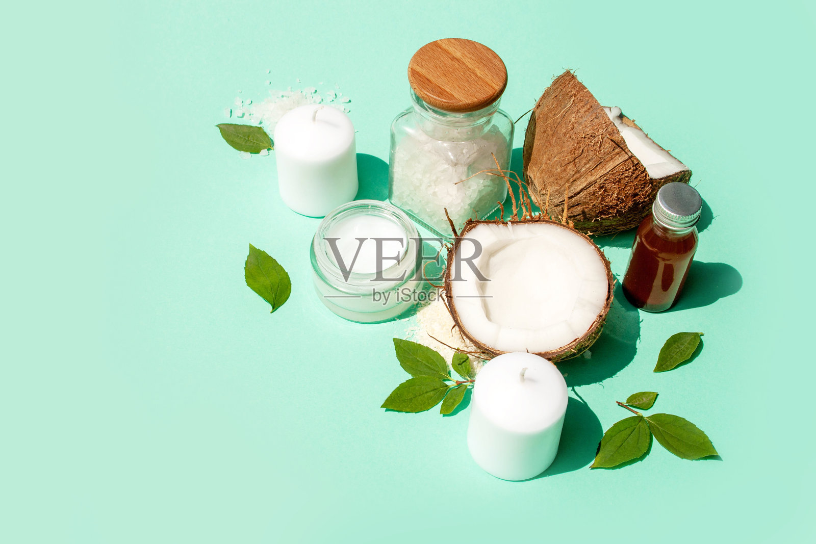 天然椰子化妆品。油，奶油，spa蜡烛和蓝色背景上的椰子楔子照片摄影图片