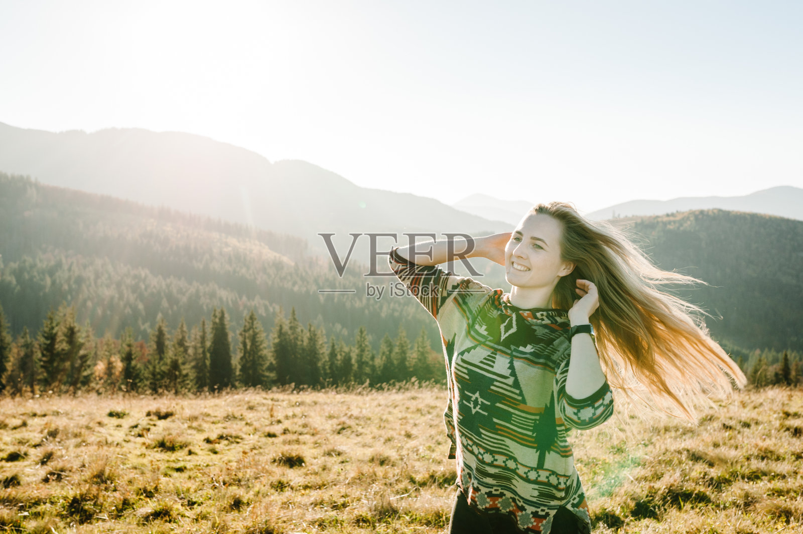 一个美丽的女人的肖像微笑和看山在日落。幸福快乐的潮人。女孩在秋天的田野里笑着。世界旅游日。特写镜头。照片摄影图片