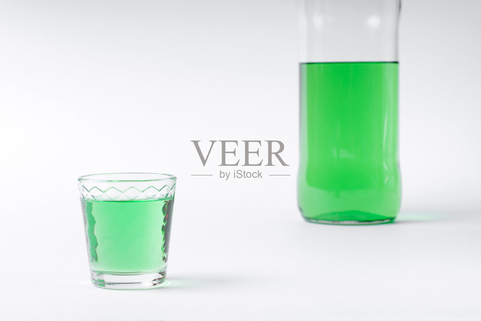 绿色烈酒装在小酒杯和瓶子里照片摄影图片