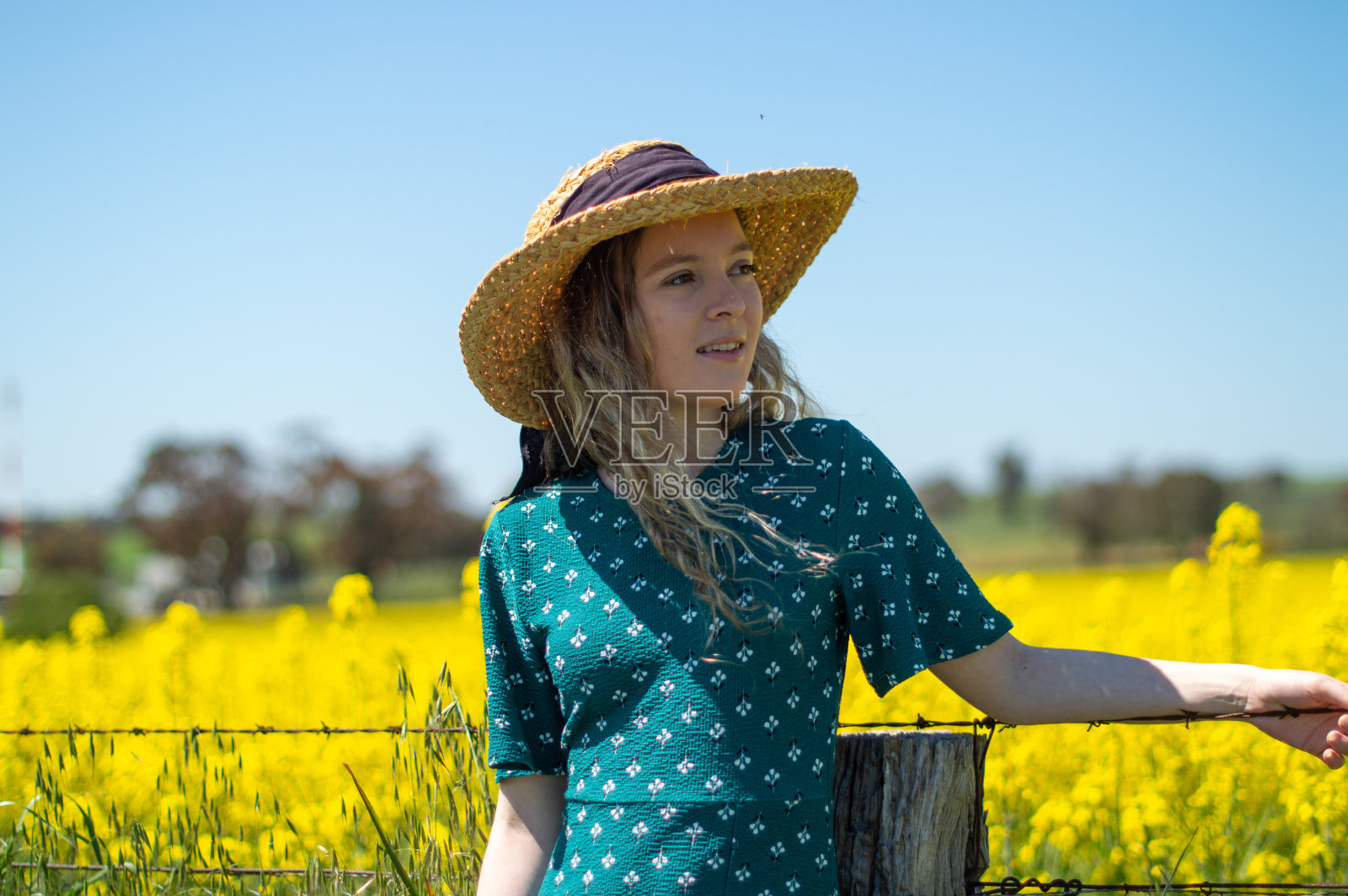 漂亮女人站在鲜艳的黄色菜籽田前照片摄影图片