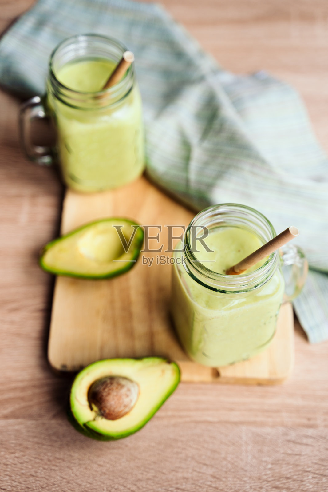 牛油果和香蕉制成的奶油冰沙，放在玻璃杯子里，纸管放在灯光背景上。没有塑料。健康食品。俯视图照片摄影图片