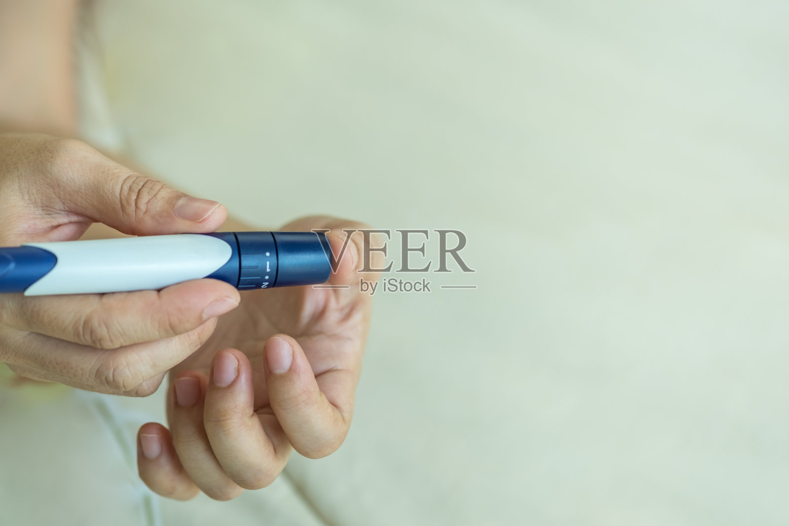 特写妇女的手用刺针在手指上检查血糖水平的血糖仪。用作医药，降糖，降血糖，保健和人的理念。照片摄影图片