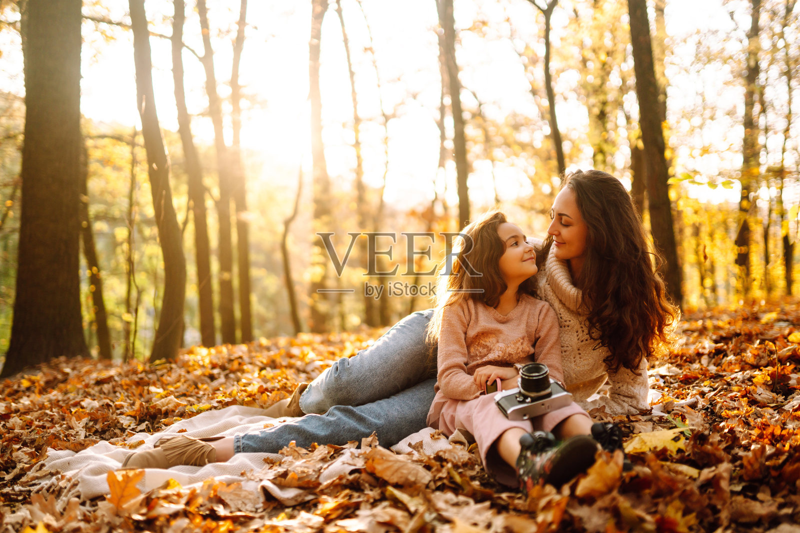 年轻的母亲和女儿一起在秋天的森林里玩。在秋天公园休息。照片摄影图片