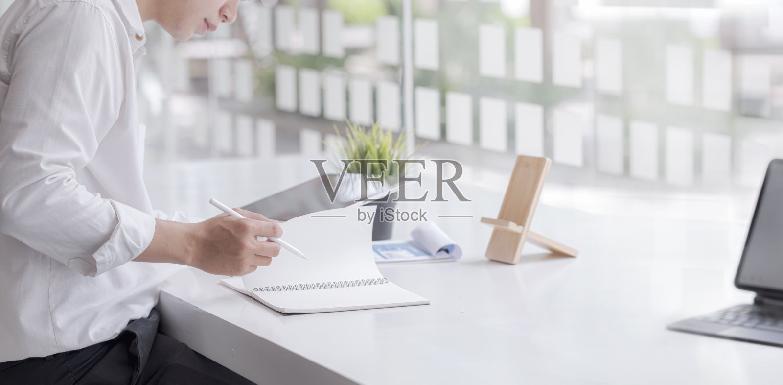 年轻的商人与文件和使用平板电脑，坐在桌子上的现代办公室，全景照片摄影图片