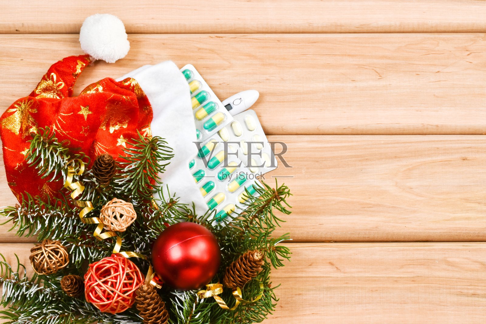 医学的圣诞节。药丸，礼物礼盒，圣诞老人帽，温度计和杉木树枝上的木制背景。医学概念。贺卡。新年和圣诞节。复制空间，平铺。照片摄影图片