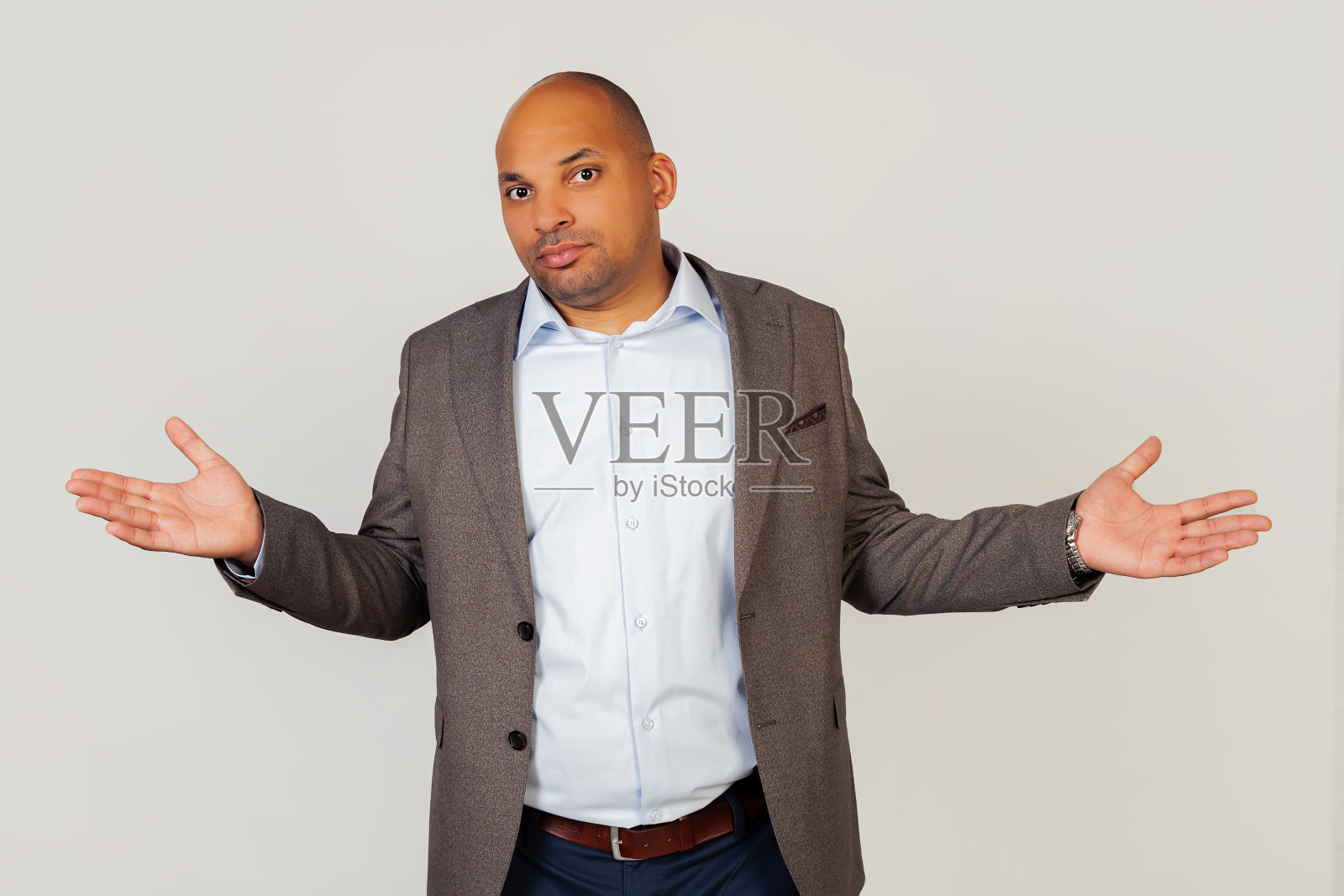 沮丧、紧张和不安的年轻非裔美国商人，带着愤世嫉俗和愤怒的表情，无助地张开双手，好像不知道该怎么办照片摄影图片