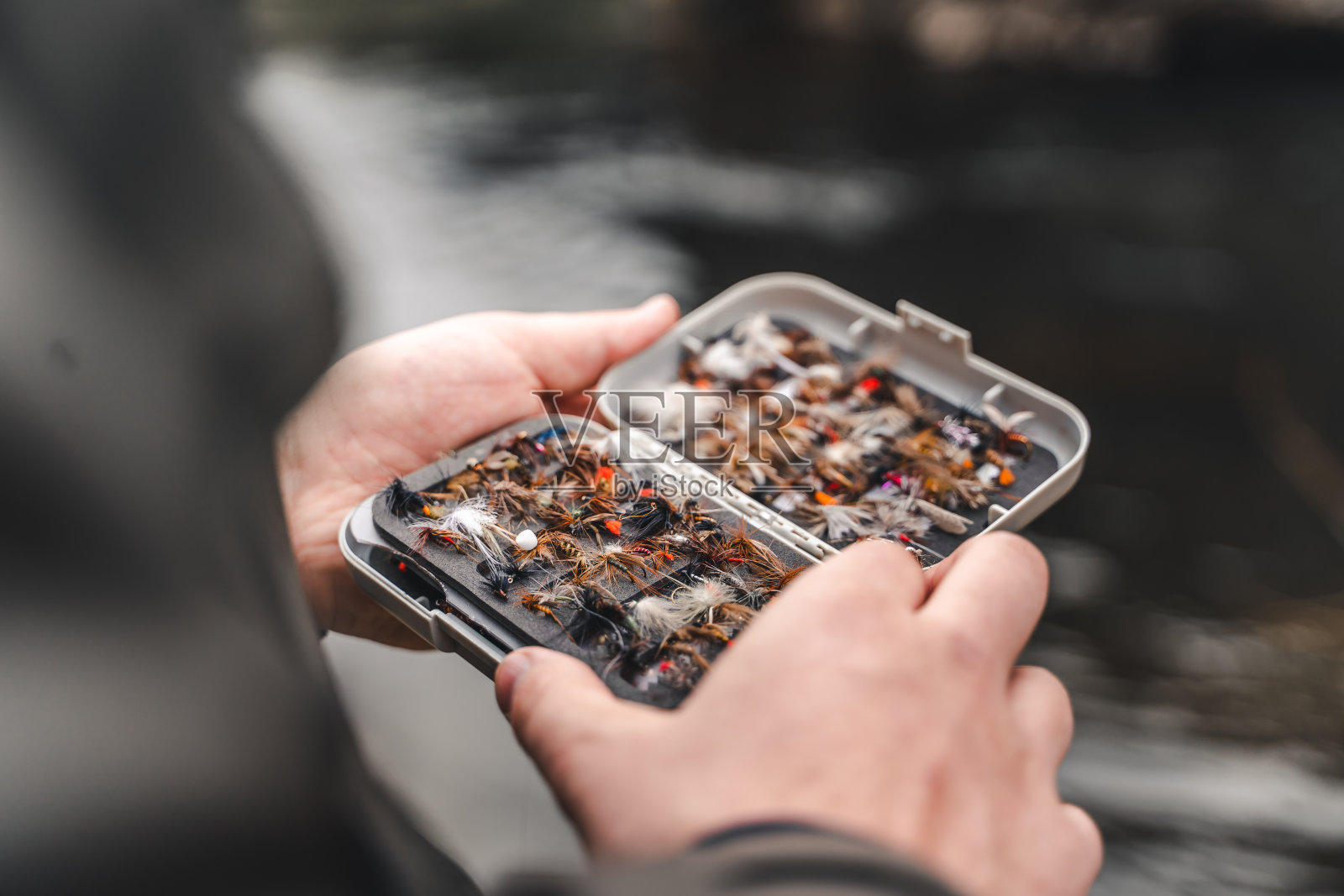 渔夫手里拿着鱼饵箱照片摄影图片