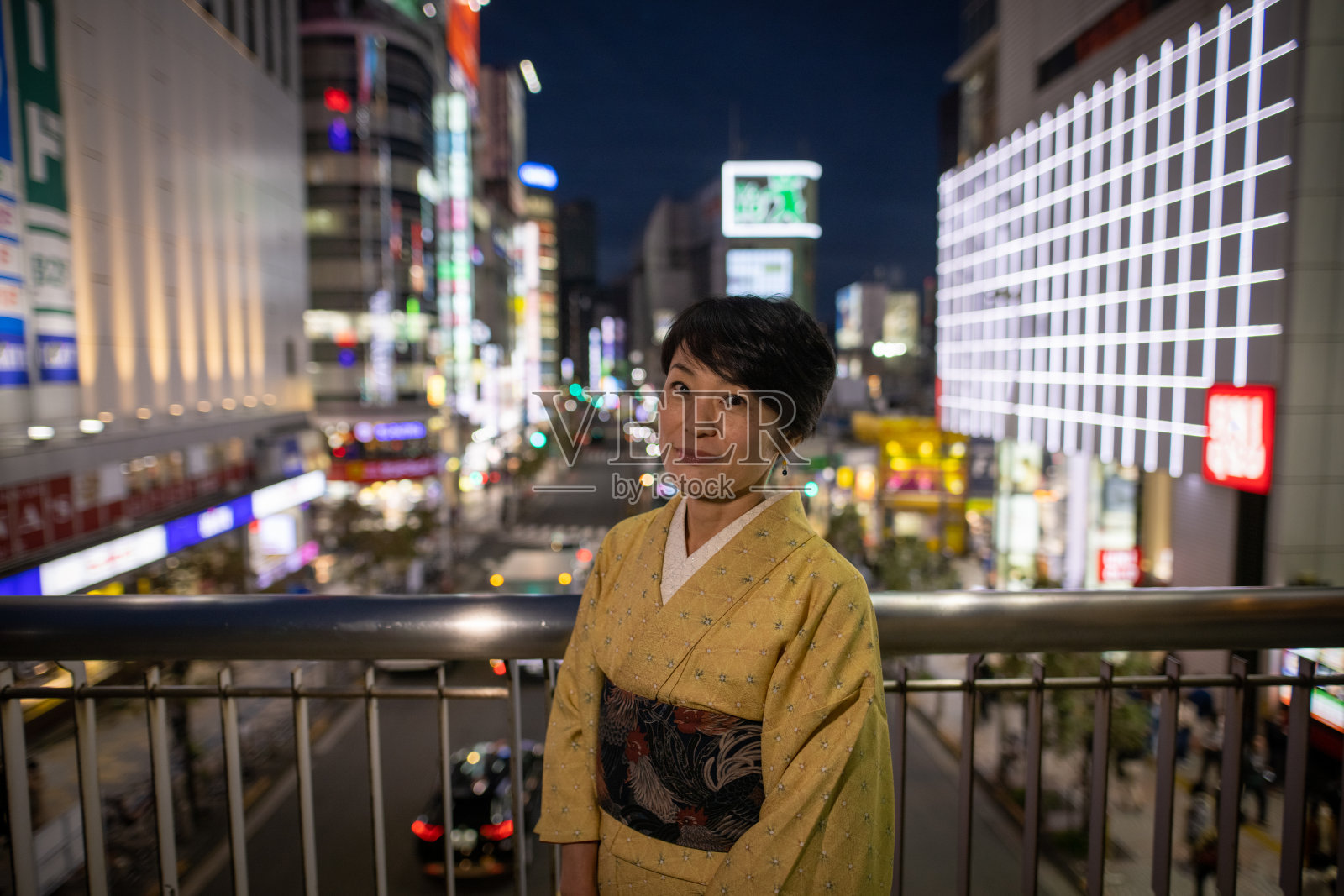 日本妇女在黄色的“和服”站在夜晚的城市肖像照片摄影图片