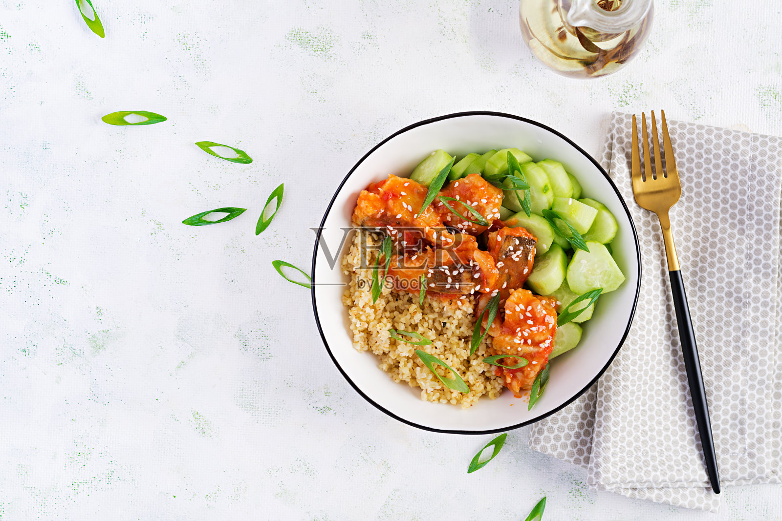 用蕃茄汁煮熟的鱼片，配上干干小麦和黄瓜，放在浅背景的盘子里。健康饮食的概念。简单的烹饪。俯视图，平放，复制空间照片摄影图片