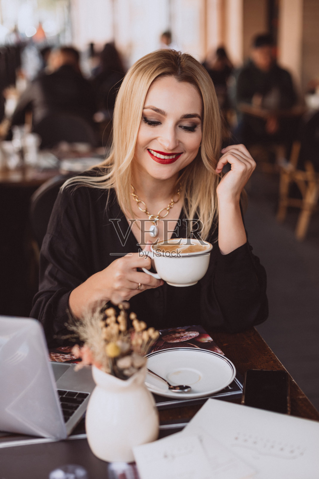 美丽的年轻商务女性与笔记本电脑享受一杯咖啡在咖啡馆在午餐休息在秋天。柔和的选择性聚焦，艺术的噪音。照片摄影图片