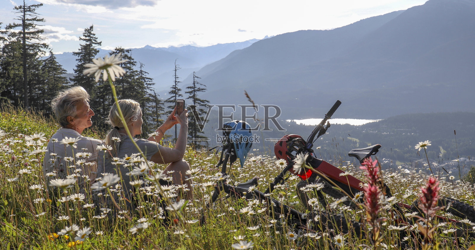 一对夫妇骑着山地电动自行车在高山草地的野花中放松照片摄影图片