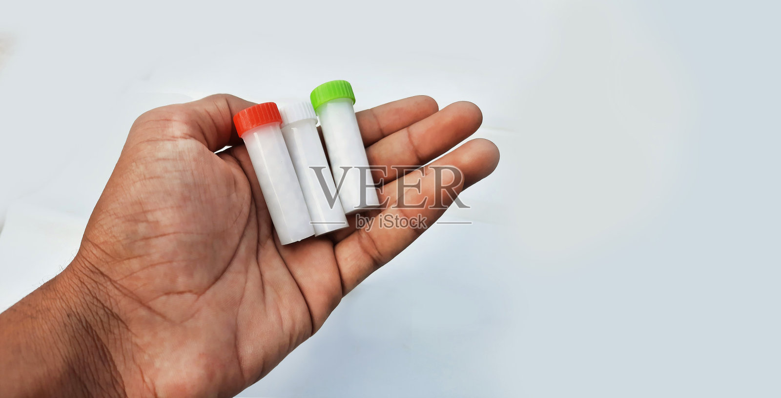 在白色的背景中拿在手里的小瓶顺势疗法药丸照片摄影图片