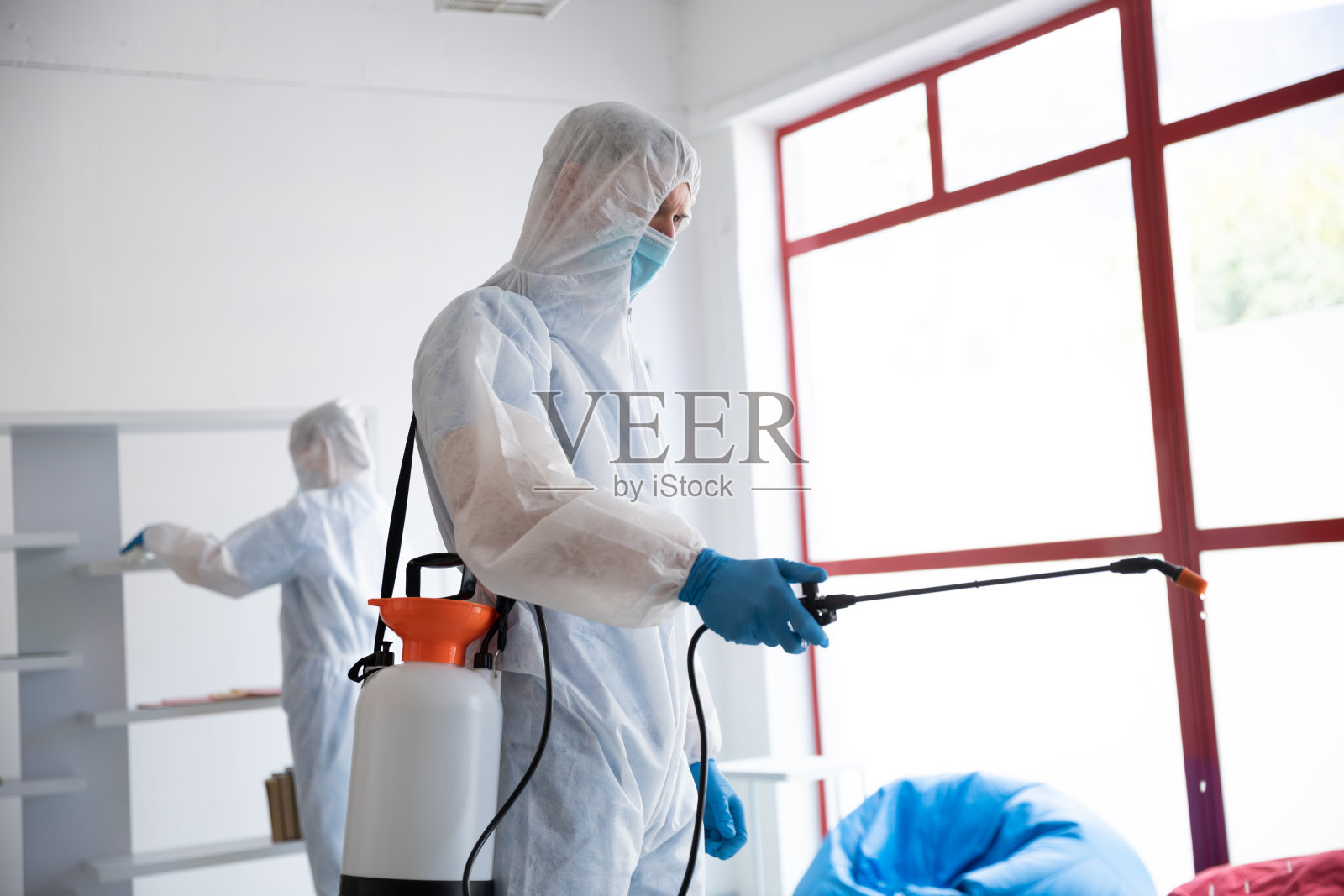 卫生工作者穿着防护服，用消毒剂清洗照片摄影图片