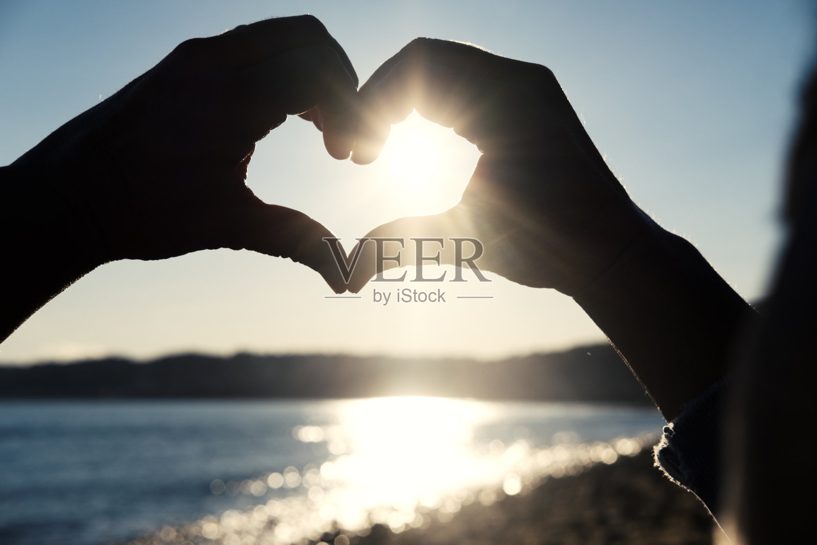 夕阳穿过心形的手照片摄影图片