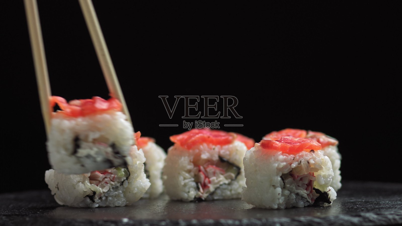 在一家日本餐厅吃午餐。男人吃寿司。费城寿司，由鱼，鲑鱼，米饭，黄瓜制成。寿司餐厅，寿司外卖。有选择性的重点照片摄影图片