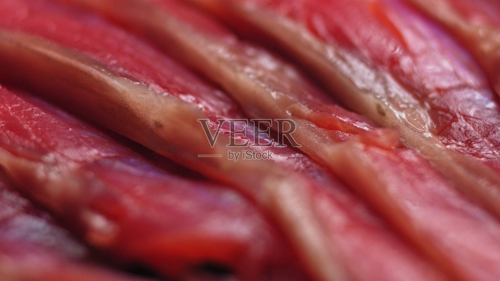 近距离拍摄平稳旋转的鲑鱼，寿司的烹饪过程-费城，燃烧的火烟新鲜生的红色金枪鱼鲑鱼鳗鱼。Makro照片摄影图片