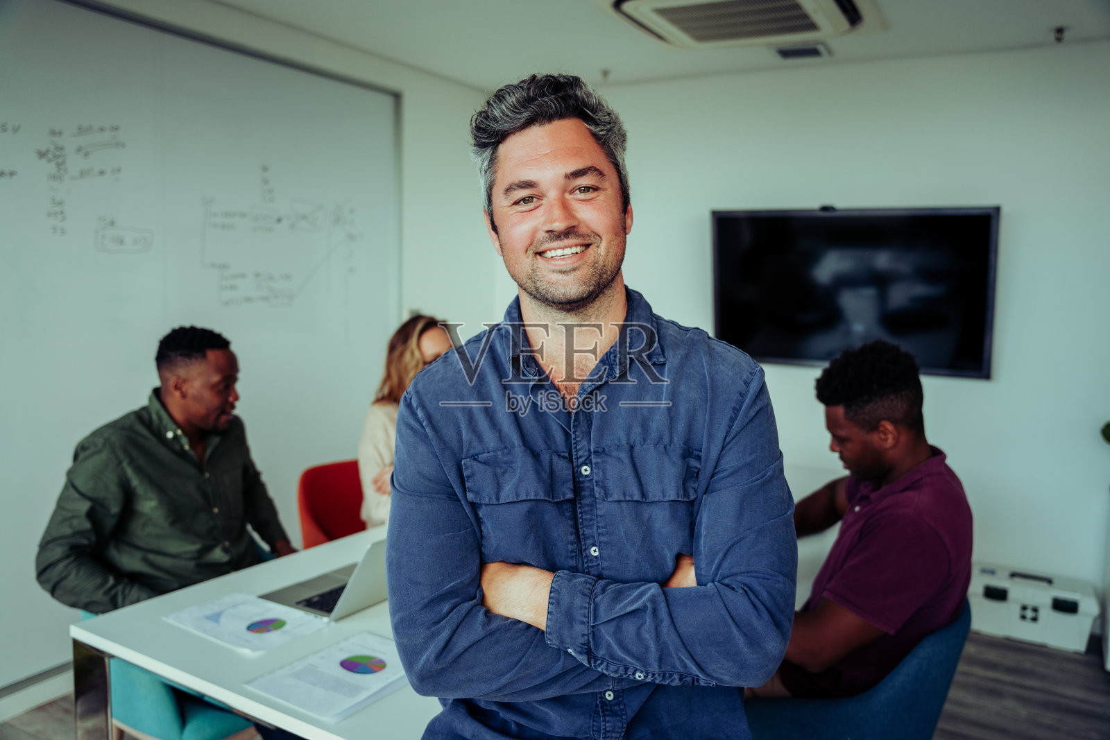 一个白人商人在会议室里自豪地双手交叉站在同事面前开会照片摄影图片