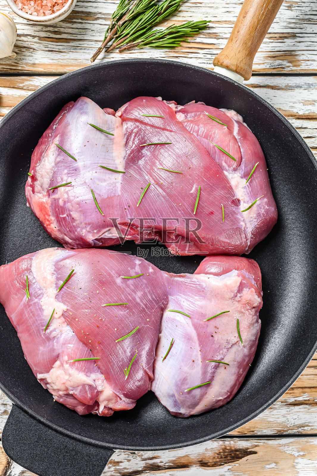 烹饪前将火鸡大腿放入锅中。光木制背景。俯视图照片摄影图片