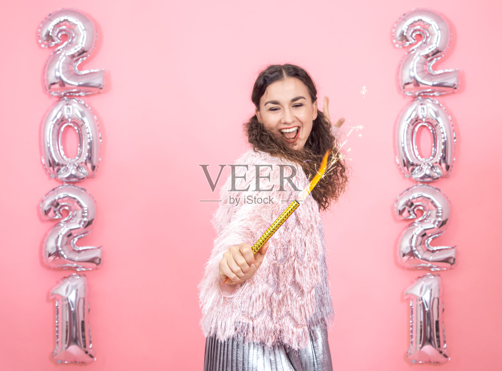 粉色背景上的年轻女子用银色气球表示2021年的数字照片摄影图片