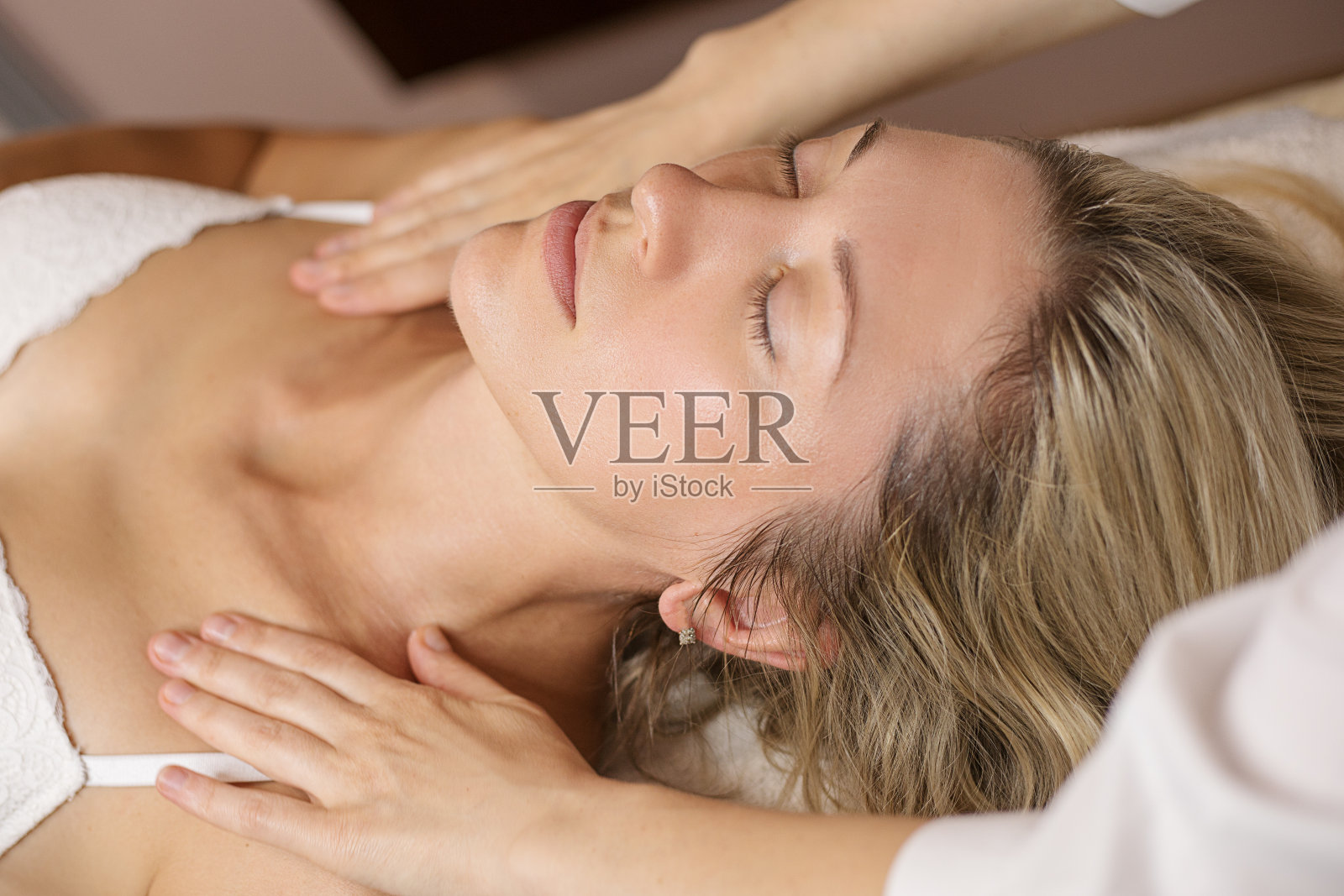 年轻女子在水疗沙龙享受面部护理。一个美丽的白人客户35岁接受皮肤护理治疗程序在诊所。按摩疗法，抗衰老。照片摄影图片