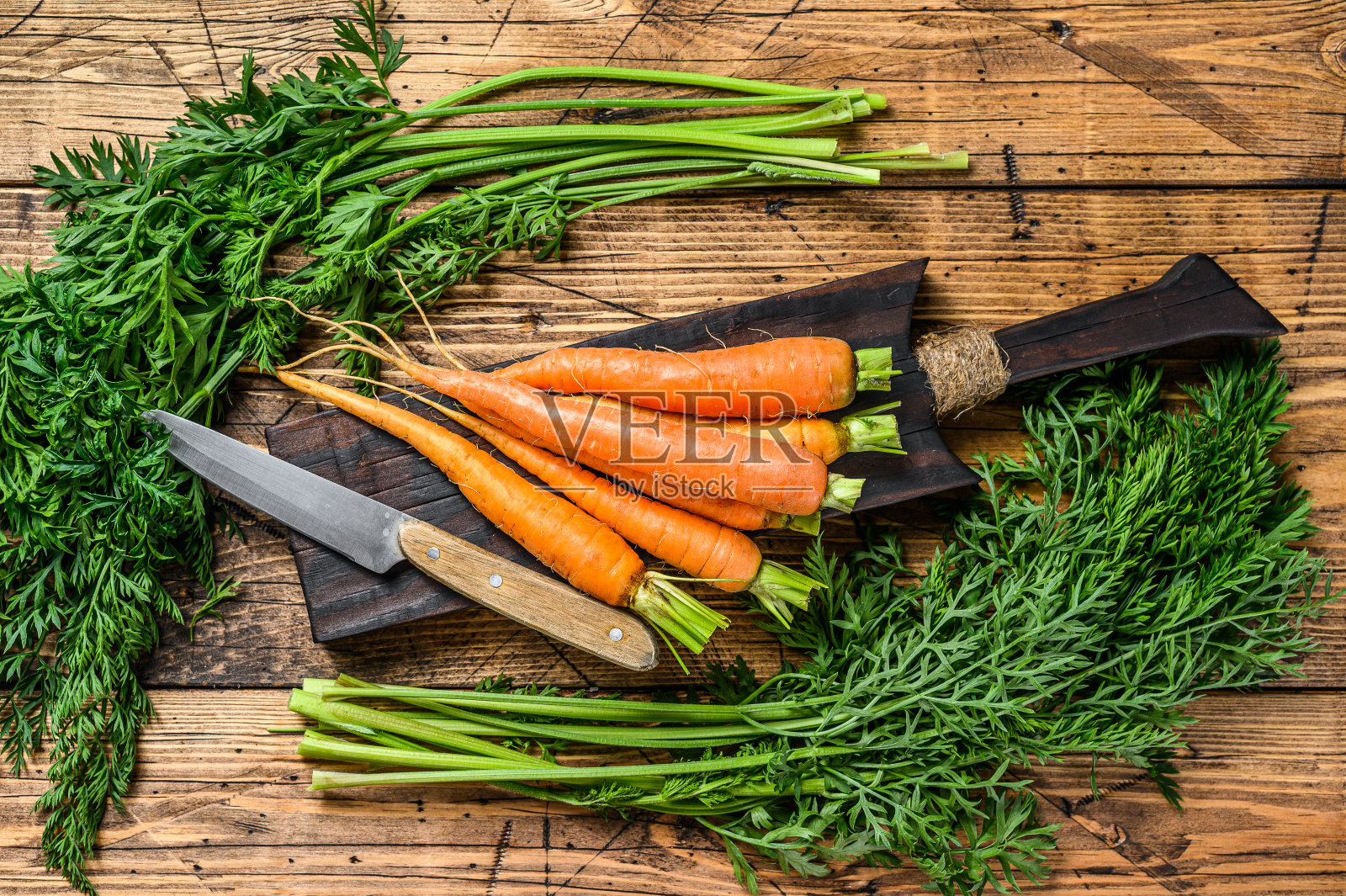 农民们把胡萝卜的顶部削掉了。木制背景。俯视图照片摄影图片