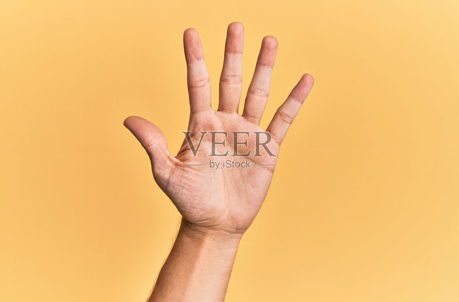 白种人的手臂和手在黄色的孤立背景上，数着5号，显示出5根手指照片摄影图片