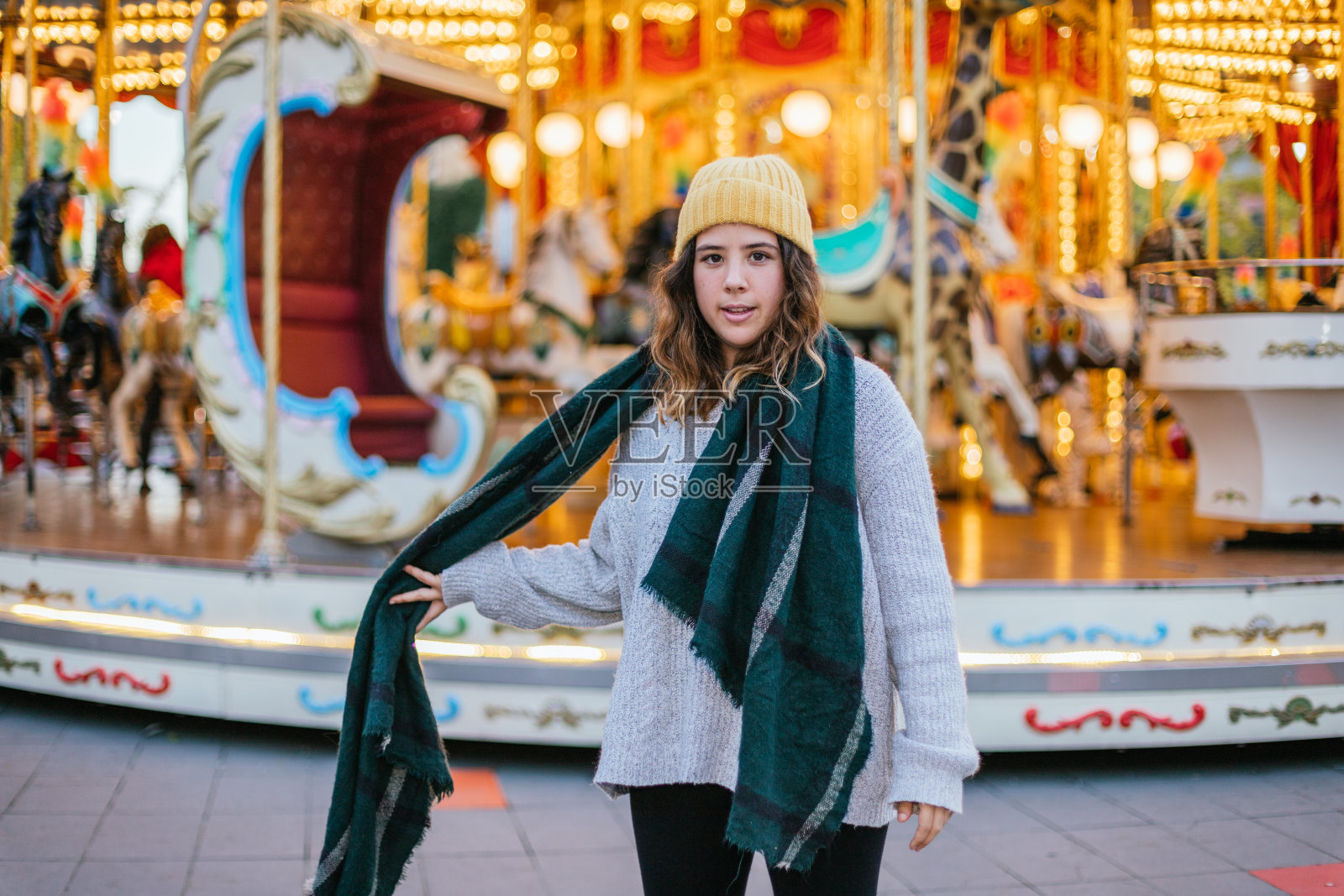 在圣诞集市上戴着黄色羊毛帽子和围巾的年轻女孩照片摄影图片