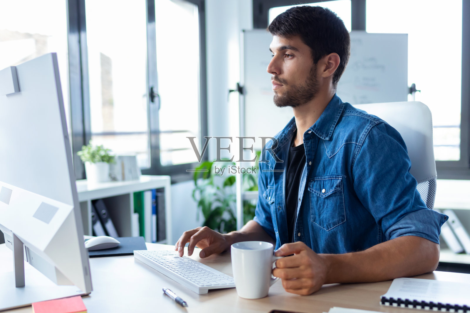 在现代的创业办公室里，软件开发员一边喝咖啡，一边用电脑工作。照片摄影图片