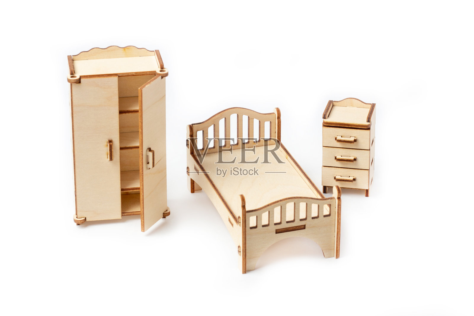 白色背景上摆放着玩具微型木制卧室家具。床，衣柜，床头柜和五斗柜。玩偶和玩具屋的家具照片摄影图片
