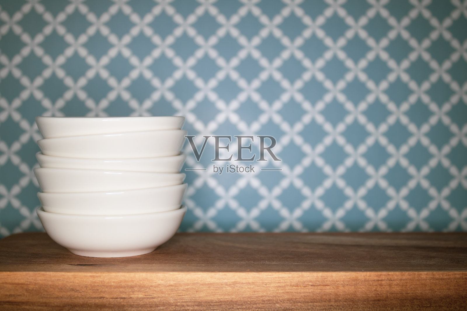 白色碗堆放在木质表面和图案背景上照片摄影图片