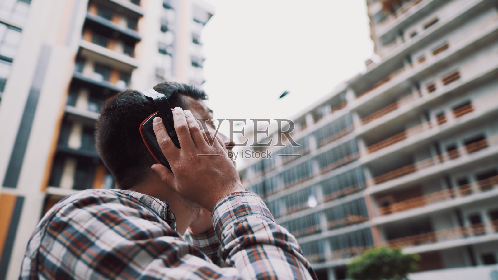 建筑工捂住耳朵，用耳套保护工人的耳朵。建筑工人戴着护耳器。施工理念，在工作中注意安全。防止受伤照片摄影图片