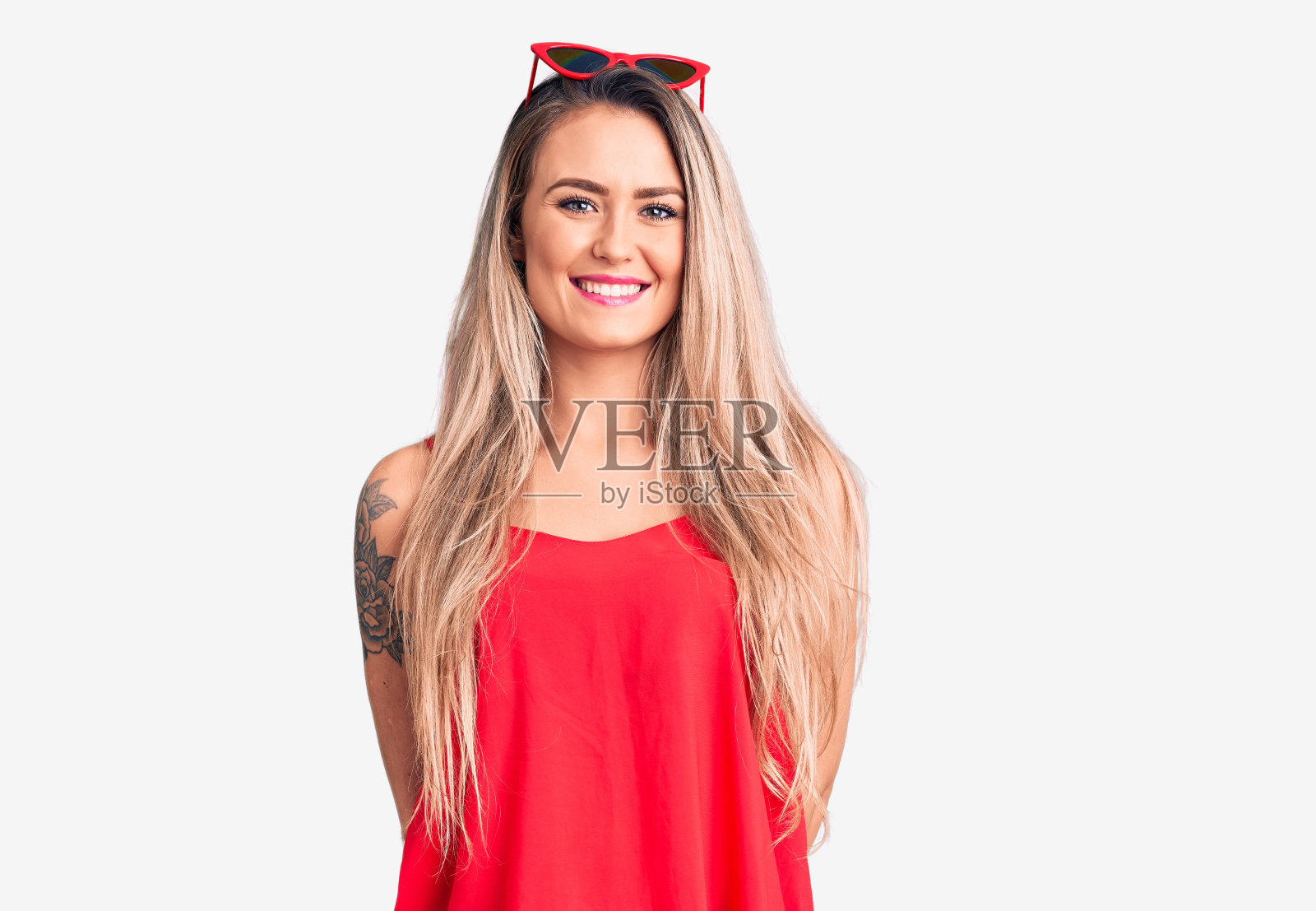 年轻漂亮的金发女人穿着无袖t恤和太阳镜，脸上带着幸福和凉爽的微笑。幸运的人。照片摄影图片