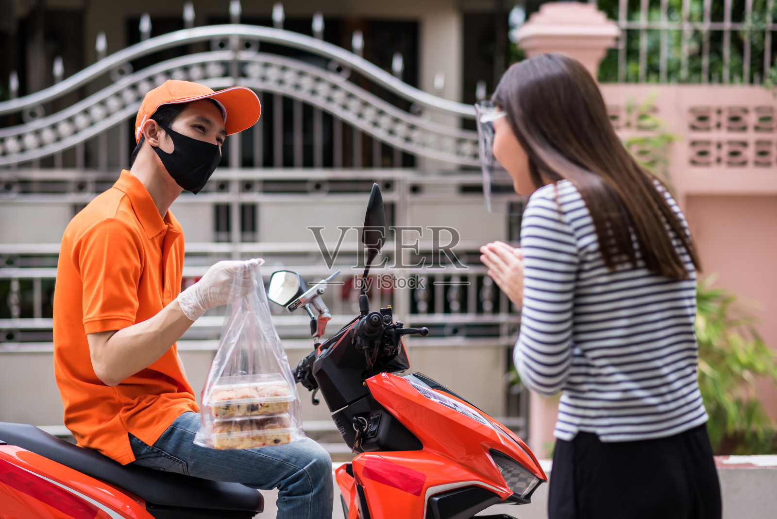 戴着口罩的疯狂快递员看着延误的顾客照片摄影图片