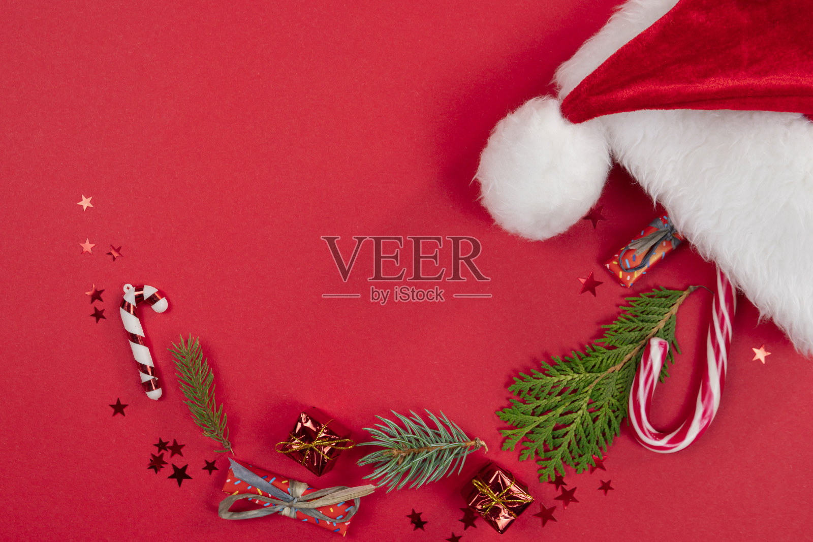 圣诞背景，平躺。圣诞老人的帽子装饰和冷杉树枝在红色的背景照片摄影图片