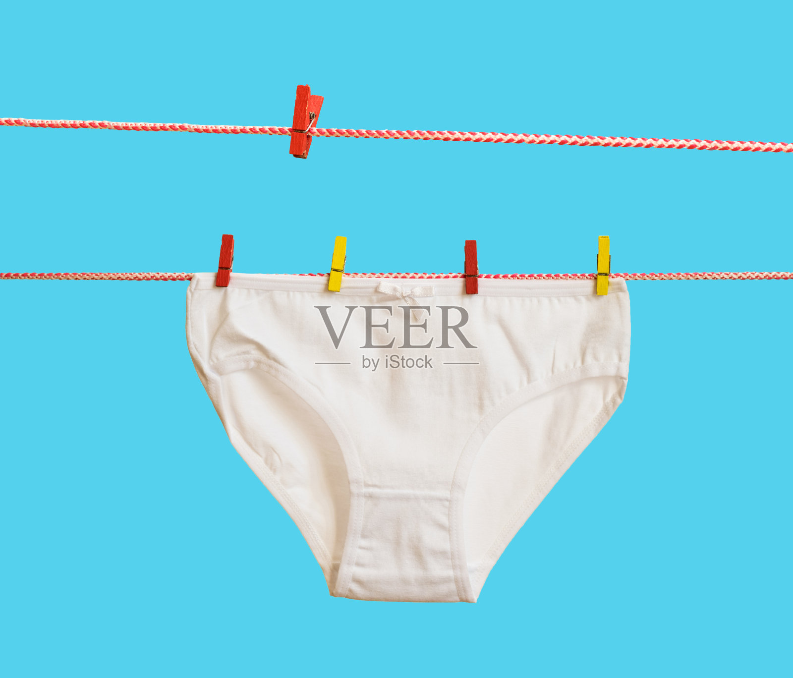 蓝色背景上的两条晾衣绳和女士内裤。照片摄影图片